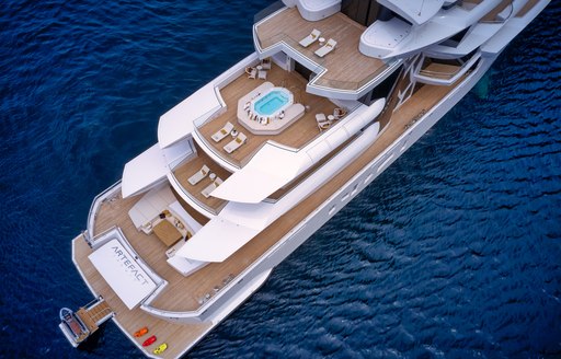 Aerial view of superyacht ARTEFACT. Plunge pool visible on deck with sun loungers located on each aft deck. Surrounded by sea. 