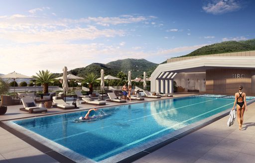 Swimming pool facility at hotel SIRO. One visitor swimming with another lady walking with a towel. Sunloungers on far side.