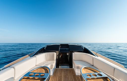 Wooden decking with cream sofas either side of boat, looking towards dark sunken deckhouse