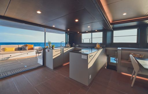 The galley aboard the  Silent 62 3-Deck Open features grey U-shaped countertops and easy access to the aft deck