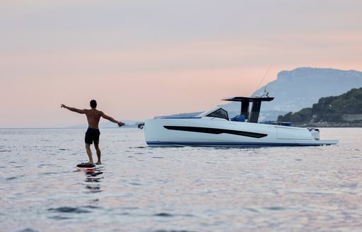 A man enjoying watersports in a calm sea with the Fiart Yachts Seawalker 35 at anchor in the background