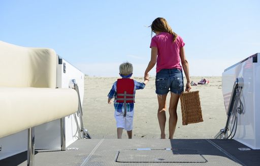 Mother and young son stepping off of beachlander tender onto beach