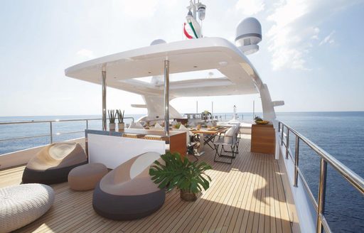 Overview of a sun deck onboard a Benetti motor yacht, with bean bag seating in the foreground and alfresco dining aft