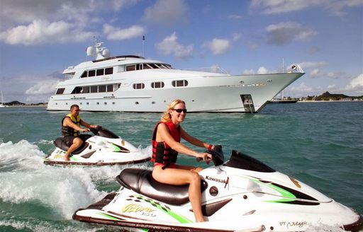 two charter guests on PWC in front of superyacht on anchor