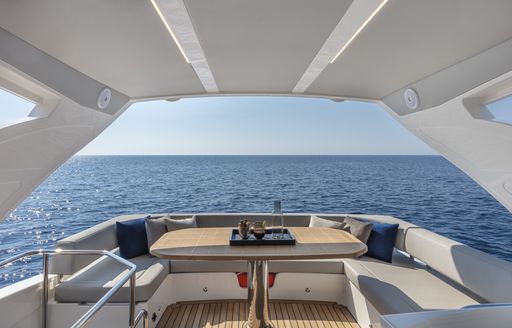 Exterior seating on the Absolute 50Fly flybridge, U shaped seating arrangement around a table, overlooking sea in background