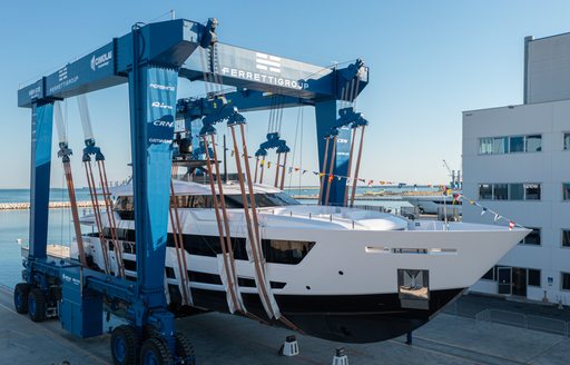 Custom Line 140 sat in crane awaiting deployment to water. Decorated with flags for launch ceremony.