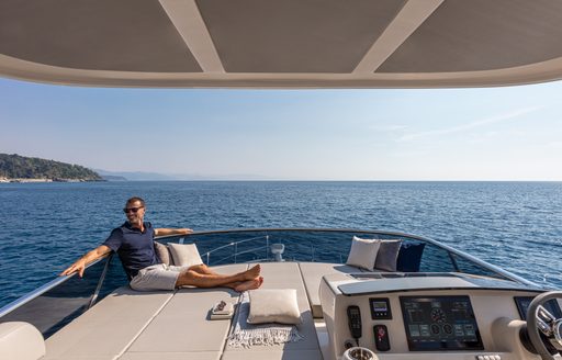 Sunpads on Absolute 50Fly flybridge, Owner relaxing on sunpad looking out at the view, surrounded by sea