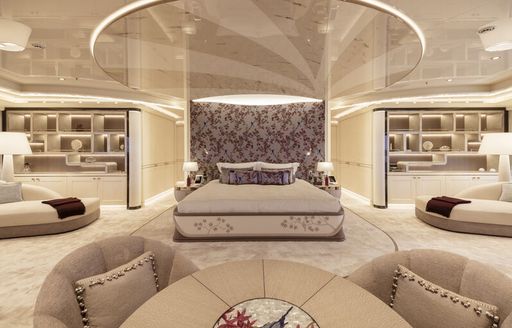 Overview of the master cabin onboard superyacht Lady Jorgia. Central berth with plush seating either side and display cases in the background.