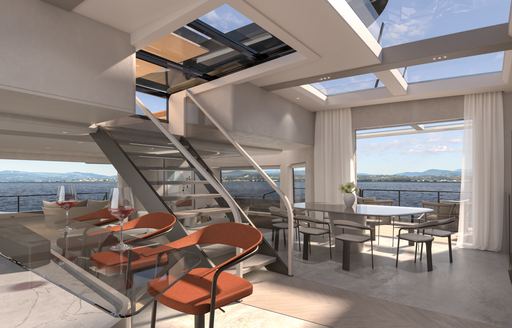 Central staircase onboard Extra Yachts VILLA X30 catarmaran. Interior dining option at base of stairs with large panoramic windows in background.