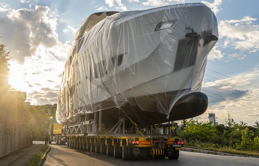 Frontal view of Numarine 26XP bow sat on a trailer, covered in protective wrapping surrounded by road and green foliage