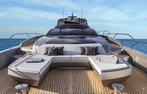 U-shaped seating in front of a raised sun bed area and with teak floors on the foredeck of the Argo 90 yacht