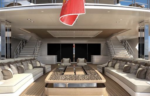 Sundeck on LANA superyacht. Large comfortable sofas and large rectangular table in the center with stairs going up behind.