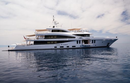 Amels 200 yacht MOONSTONE shown anchored in still water on cloudy day, water level towards starboard side profile