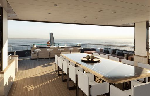 Dining area onboard Project Rinascimento, long 12 seater table overlooking sea views aft.