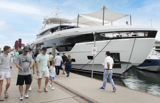 A superyacht berthed at the Miami International Boat Show with visitors walking past