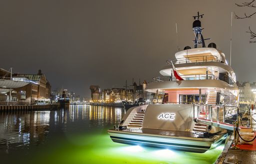 ACE C144S shown at night time in busy harbor with yachts in background, yacht has night lights illuminating the water