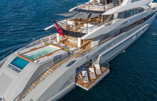 Superyacht TATIANA aft decks, infinity pool and fold down balcony visible, along with alfresco dining options. Surrounded by sea.