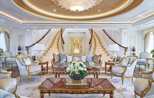 Main salon onboard ALAIYA (TIS). Ornamental seating surrounds coffee table with staircases ascending in background.