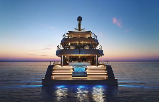 Aft view of Feadship Project Freedom at dusk, aft of yacht lit with blue underwater spots and illuminated pool