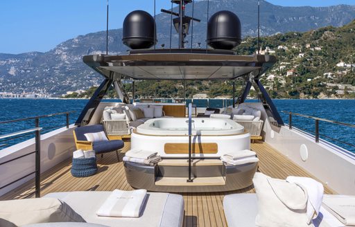 Overview of the sun deck onboard the Custom Line 140. Central Jacuzzi with sun loungers in foreground.