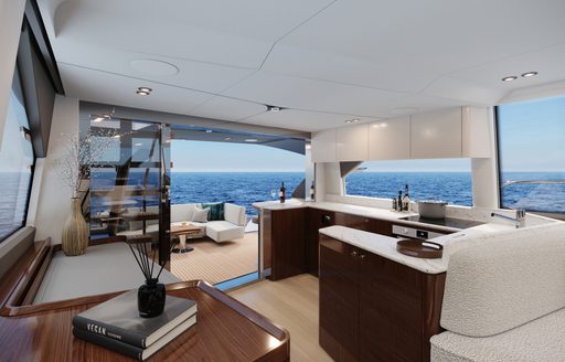 Main salon onboard Fairline Squadron 58. White seating in foreground with galley on starboard side, overlooking exterior dining area.