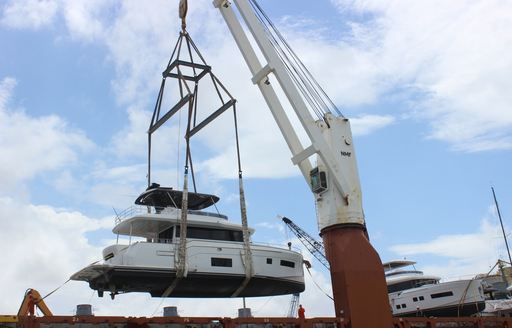 Sirena 58 on a crane, being lifted off a ship down to the sea.