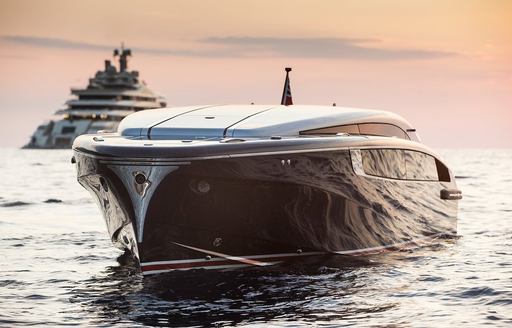 Sleek tender on sea with superyacht in background