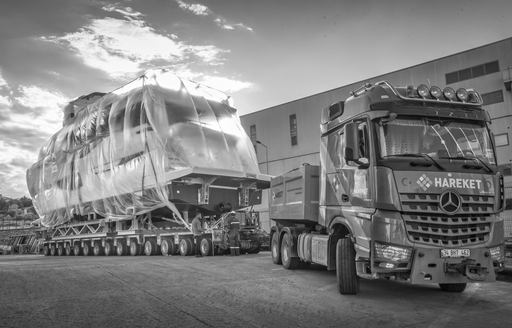 Black and white image of Numarine 26XP being pulled on a trailer alongside shipyard construction building