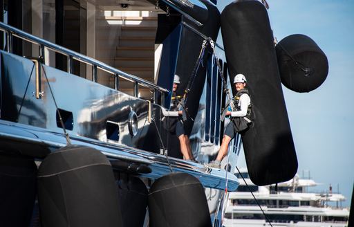 Man harnessed to the side of a motor yacht at the Monaco Yacht Show