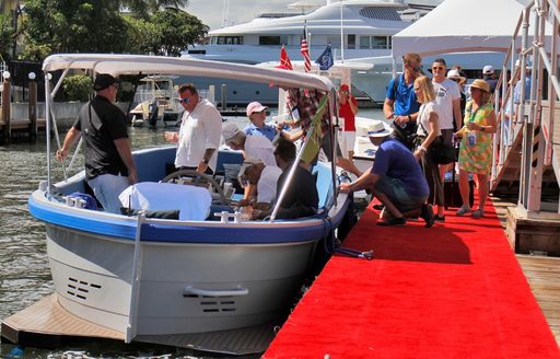 Tenders line up along a dock adorned with a red carpet, with visitors being aided on and off the boats