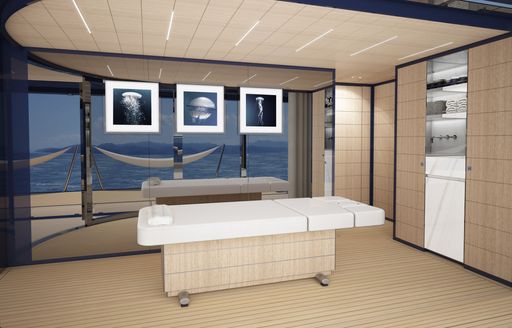 White massage bed, with photos of jellyfish on glass wall behind it, with sea visible through glass wall.