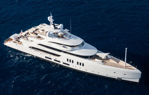 Benetti yacht CALEX shown in far aerial shot with view over starboard side and bow, dark calm waters, seemingly bright day