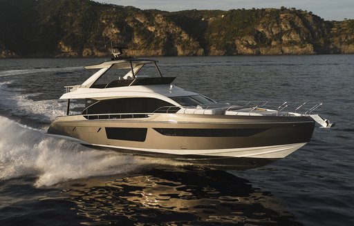 Azimut 68 Fly underway, surrounded by sea with cliffs in background.