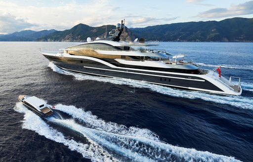 Oceanco yacht DAR running shot alongside custom yacht tender Seen from port side making way at reasonable speed in calm water, with land in background