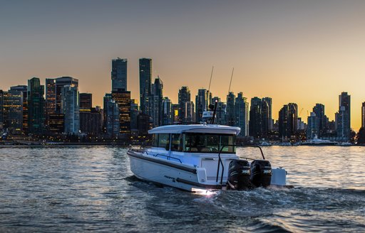 Tender boat on water with city scape in background at twilight