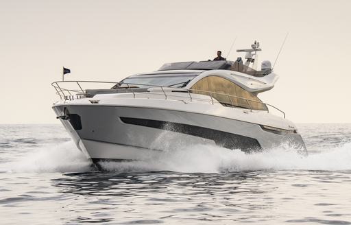 Fairline Phantom 65 running shot taken from water level towards port bow and side profile in calm seas, on moderate day, approaching half light