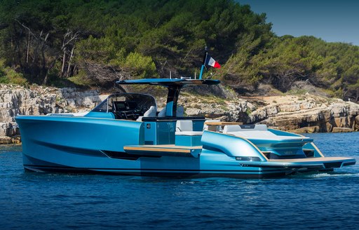 Solaris 44 Open on anchor in picturesque location in calm sea, side wings open to extend the aft deck by the water, stunning blue hull colour, bright day