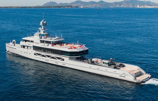 A port-side, top-down view of superyacht BOLD making way at sea with landfall in the background