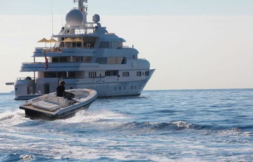 Chase boat moving at speed on sea with larger superyacht in background