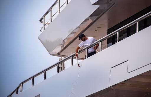 mage shows yacht crew on side of yacht preparing for display at MYS 2024