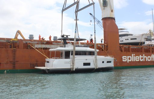 Sirena 58 attached to a crane after being lifted down to the sea from an orange ship.