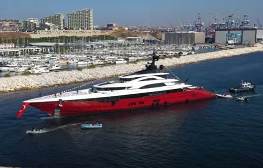 Superyacht LEONA on water after launch, surrounded by tugs and tenders.