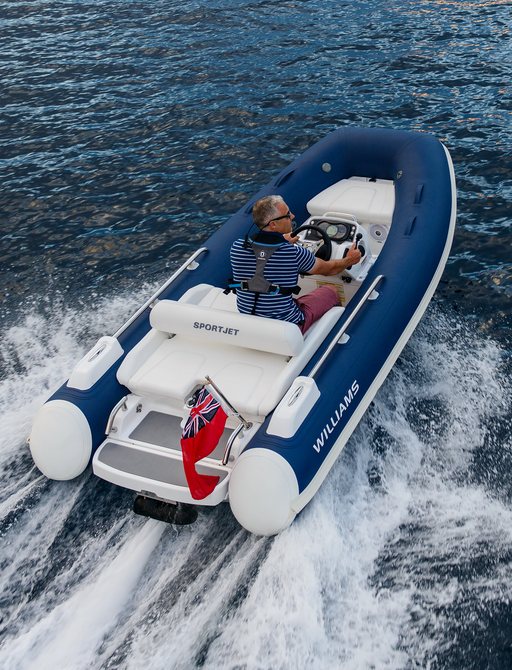 Man on small RIB tender on clear water