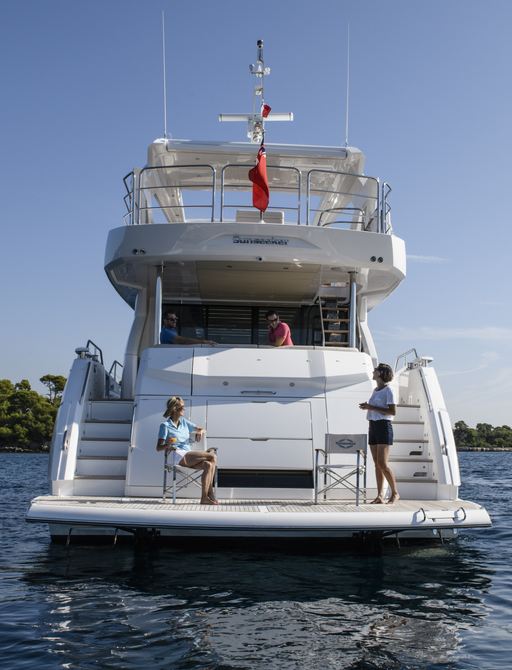 76 Yacht by Sunseeker for sale at Fort Lauderdale International Boat Show. Image shows guest on bathing platform and crew bringing a drink