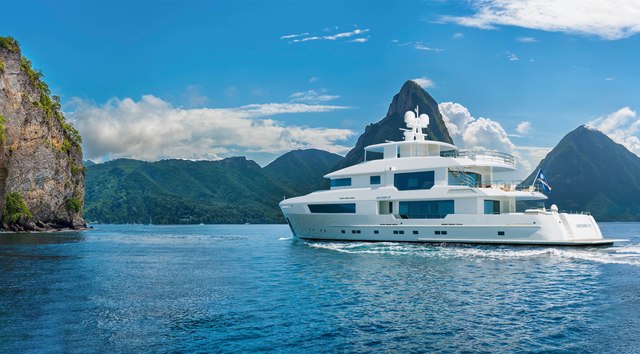 The Cheoy Lee 127 Discovery explorer yacht running through a calm sea in front of a rocky landscape