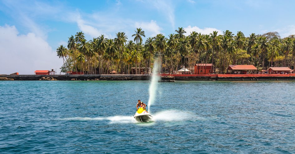 Female tourist using a Jet Ski at Ross Bay, Andaman Islands, dock and palm trees in background