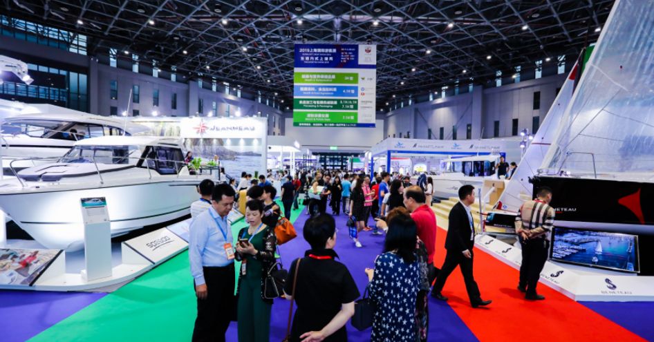 Overview of China International Boat Show in progress. Visitors looking round display of yachts.