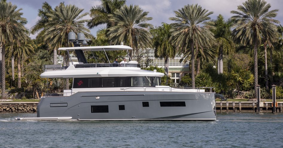 Sirena 58 underway, passing line of palm trees in the background.