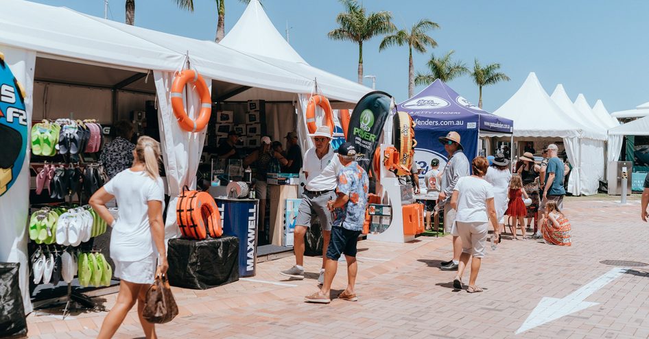 Row of exhibitors tents at Sanctuary Cove Boat Show, visitors browsing along the front.