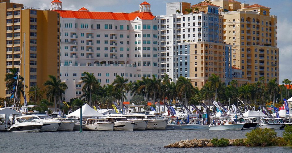 Overview of Palm Beach marina during PBIBS, multiple yachts berthed surrounded by towering hotels.